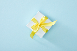 top view of festive gift box with yellow ribbon on blue background