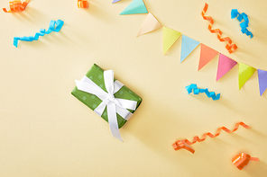 top view of festive colorful confetti and gift on beige background