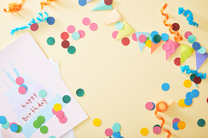 top view of festive colorful confetti and happy birthday greeting card on beige background