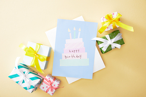 top view of festive colorful gifts and happy birthday greeting card on beige background