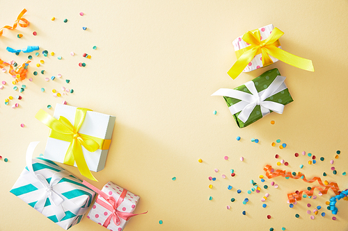 top view of festive colorful confetti and presents on beige background