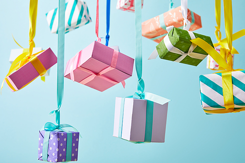 festive colorful gift boxes hanging on ribbons isolated on blue