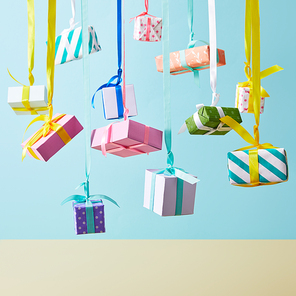 festive colorful gift boxes hanging on ribbons on blue background