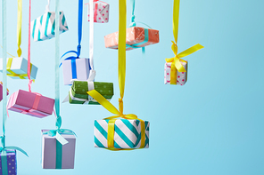 festive colorful gift boxes hanging on ribbons on blue background