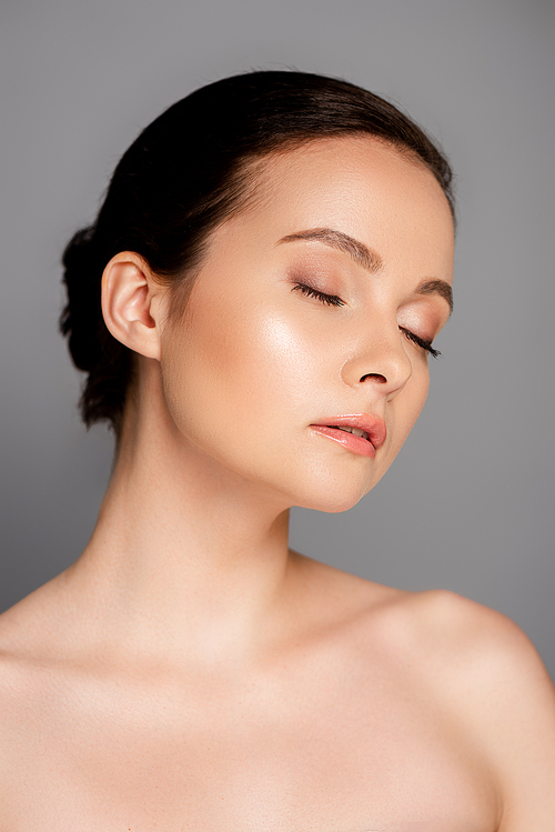 portrait of beautiful naked woman with shiny makeup and closed eyes isolated on grey