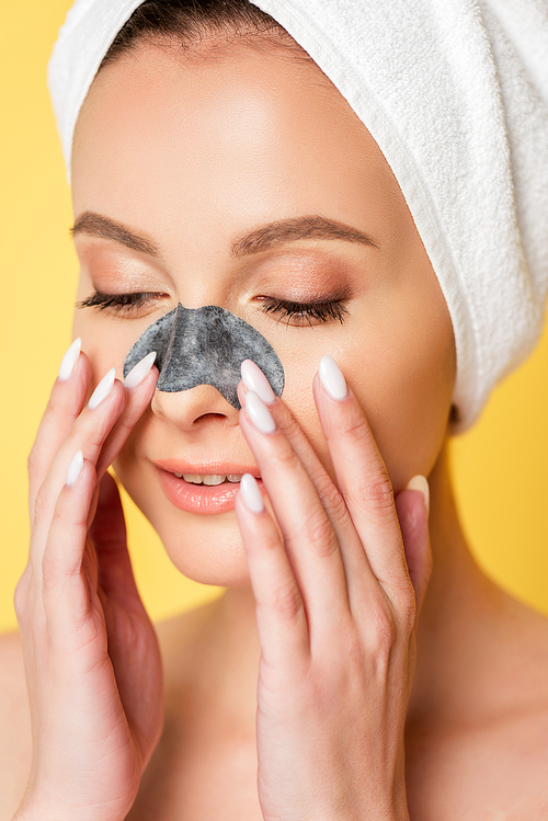 beautiful naked woman with towel on head and blackhead remover on  nose isolated on yellow