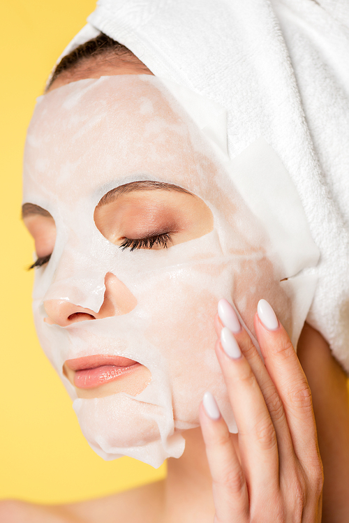 naked beautiful woman with towel on head, closed eyes and face mask isolated on yellow