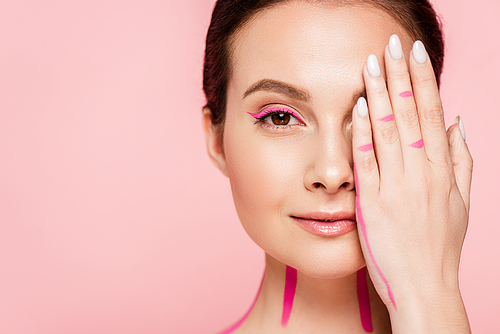 beautiful woman with pink lines on body covering face with hand isolated on pink