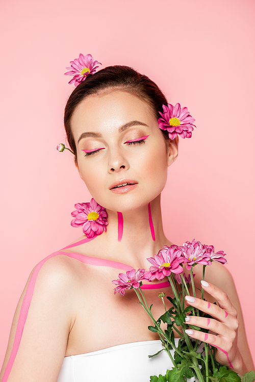 beautiful woman with closed eyes, pink lines on body and flowers in hair holding bouquet isolated on pink