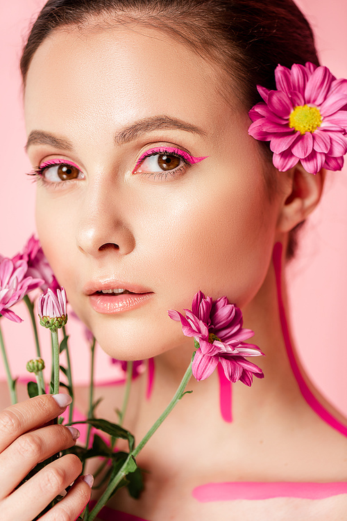 naked beautiful woman with pink lines on body and flower in hair holding bouquet isolated on pink