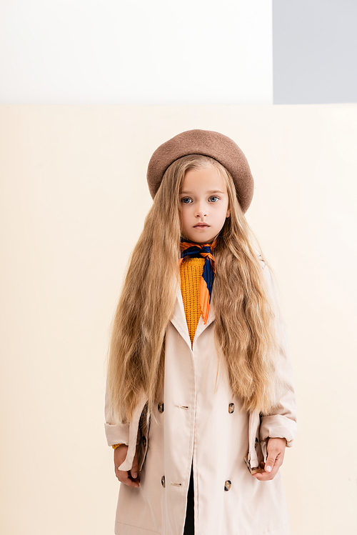 fashionable blonde girl in autumn outfit on beige and white background