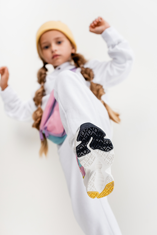 selective focus of blonde girl in sportswear posing on white background