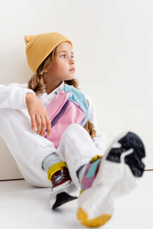 selective focus of blonde girl in sportswear sitting near white wall