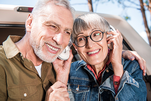 smiling senior couple of tourists listening music in headphones