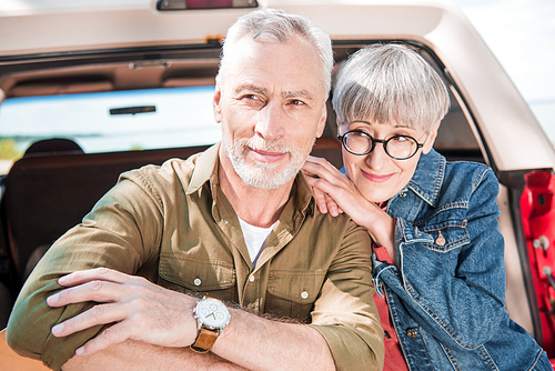 happy senior couple standing together near car in sunny day