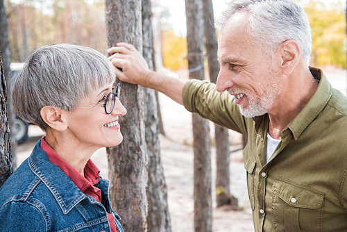 happy senior couple looking at each other and smiling in forest