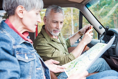 selective focus of senior couple looking at map in car