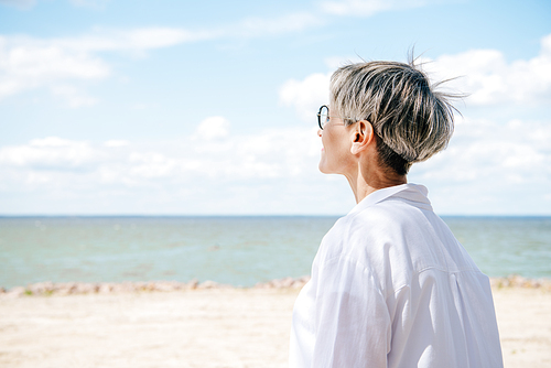 senior woman in white shirt looking away at beach