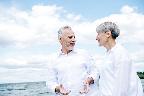 happy smiling senior couple in white shirts looking at each other under blue sky