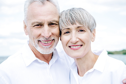 front view of smiling happy senior couple in white shirts 