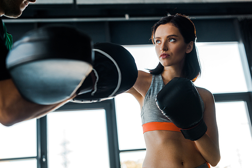 sportswoman in boxing gloves working out with sportsman in sports center