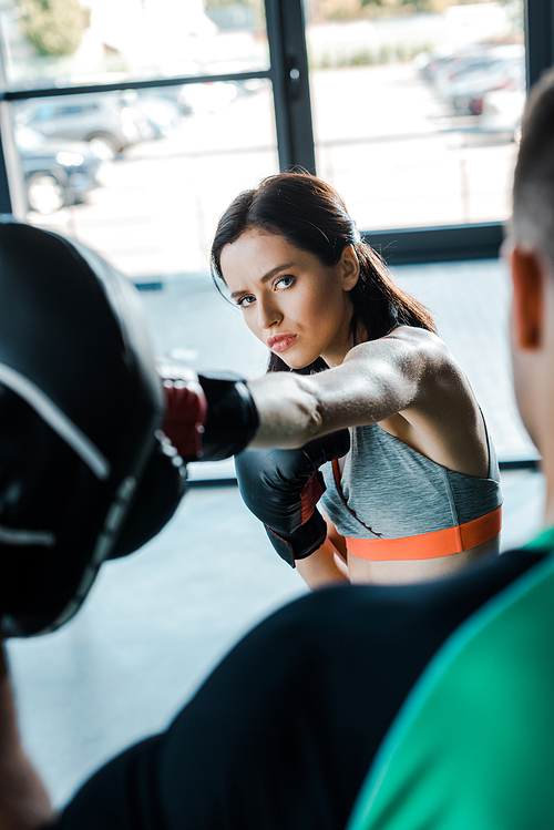sportswoman in boxing gloves working out with sportsman in sports center