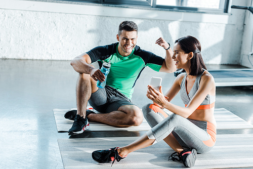 smiling sportswoman taking selfie with sportsman in sports center