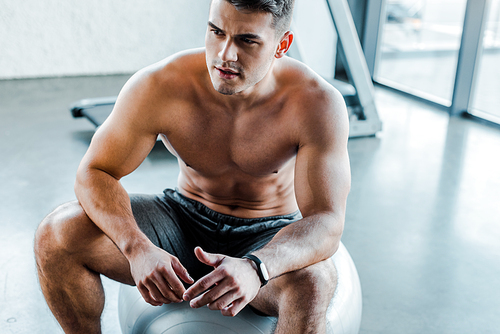 handsome sportsman sitting on fitness ball in sports center