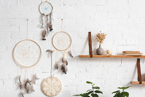 dream catchers with feathers and shelves with books on white brick wall