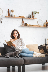 beautiful woman reading book with scottish fold cat on sofa