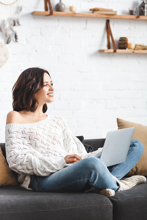 beautiful smiling girl using laptop on sofa in cozy living room