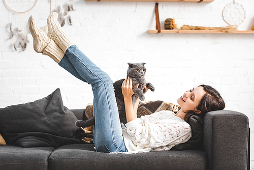 beautiful cheerful girl lying on sofa with scottish fold cat