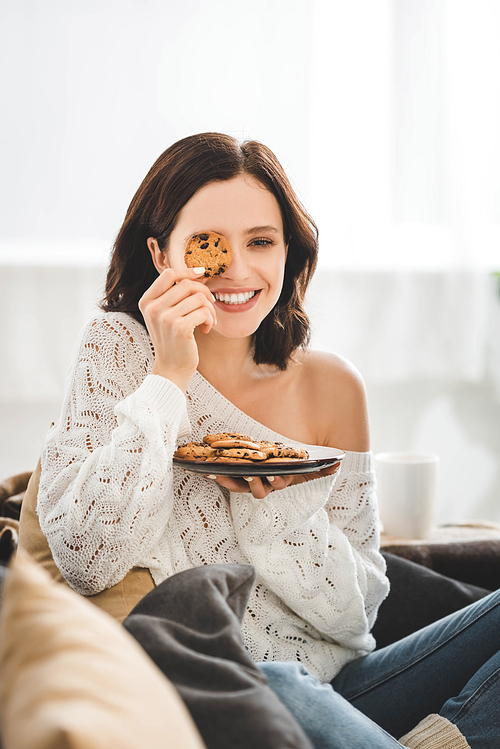 beautiful smiling girl sitting on sofa with cookies