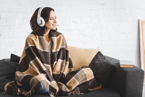 brunette woman in blanket listening music with headphones