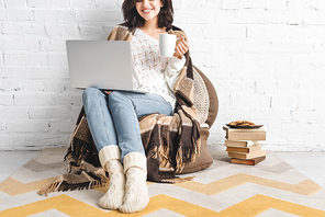 cropped view of smiling girl with cookies and coffee using laptop