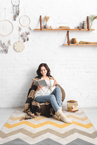 brunette girl reading book in cozy living room with coffee and cookies