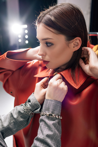 stylist touching trendy jacket on beautiful model