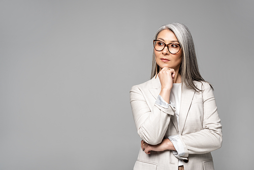 beautiful thoughtful asian businesswoman in eyeglasses isolated on grey