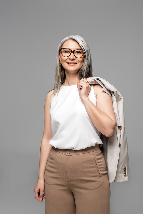 beautiful smiling asian businesswoman in eyeglasses isolated on grey