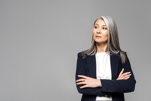 confident asian stylish businesswoman with grey hair and crossed arms isolated on grey