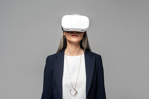 attractive businesswoman using virtual reality headset isolated on grey