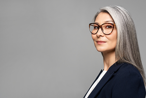 elegant asian businesswoman with grey hair in eyeglasses isolated on grey