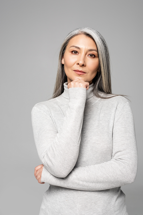 thoughtful asian woman in turtleneck with grey hair and closed eyes isolated on grey