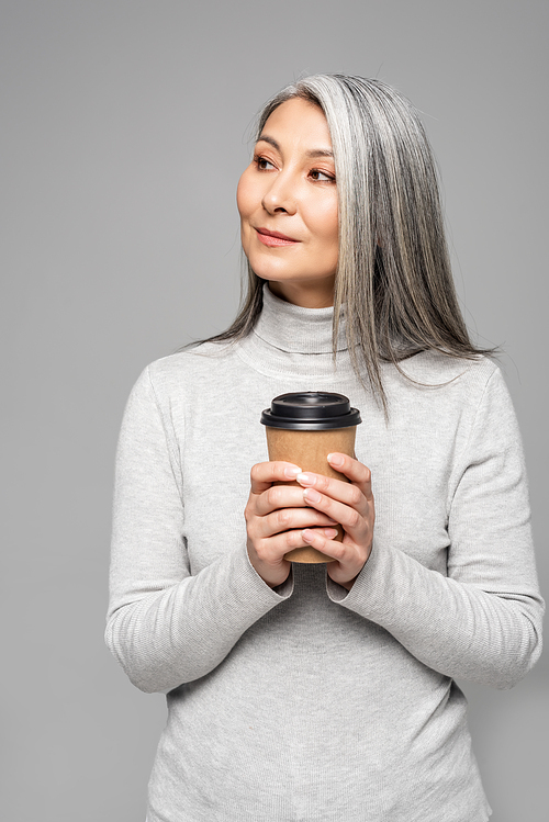 asian woman in turtleneck with grey hair holding coffee to go isolated on grey
