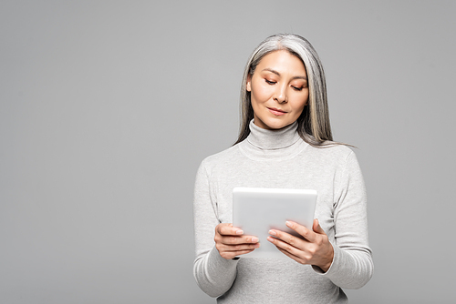 beautiful asian woman in turtleneck using digital tablet isolated on grey