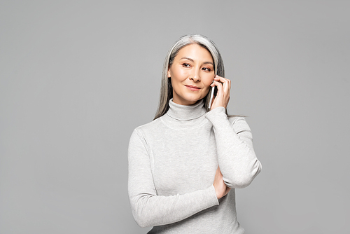 asian woman in turtleneck with grey hair talking on smartphone isolated on grey