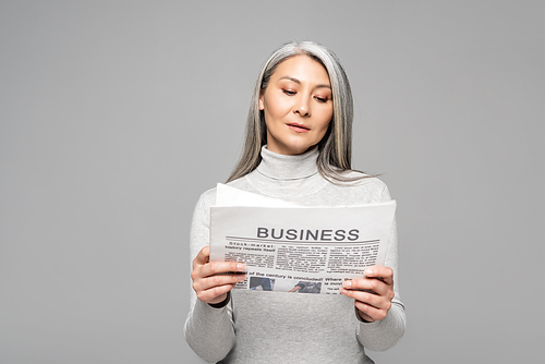 adult asian woman in turtleneck with grey hair reading business newspaper isolated on grey