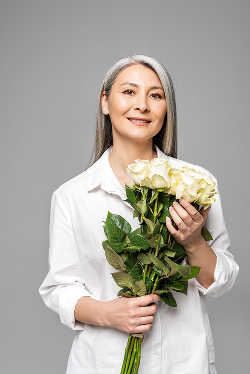 adult attractive asian woman with grey hair holding bouquet of white roses isolated on grey