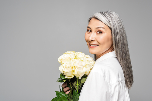 adult happy asian woman with grey hair holding bouquet of white roses isolated on grey