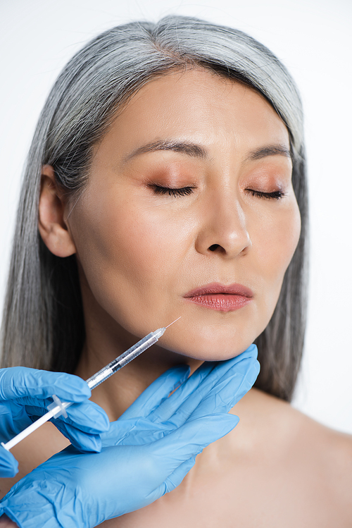 beautiful naked asian woman and doctor in latex gloves holding syringe with beauty injection isolated on grey